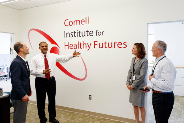 People standing in front of the Cornell Institute for Healthy Futures logo printed on the wall