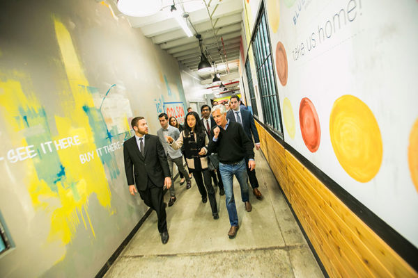 Group of people walking down hallway with quotes and imagery painted on wall