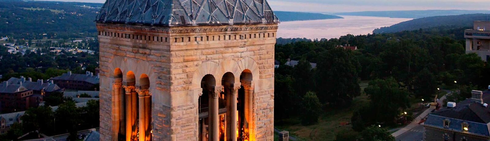McGraw Clock tower illuminated with Cayuga Lake in the background.