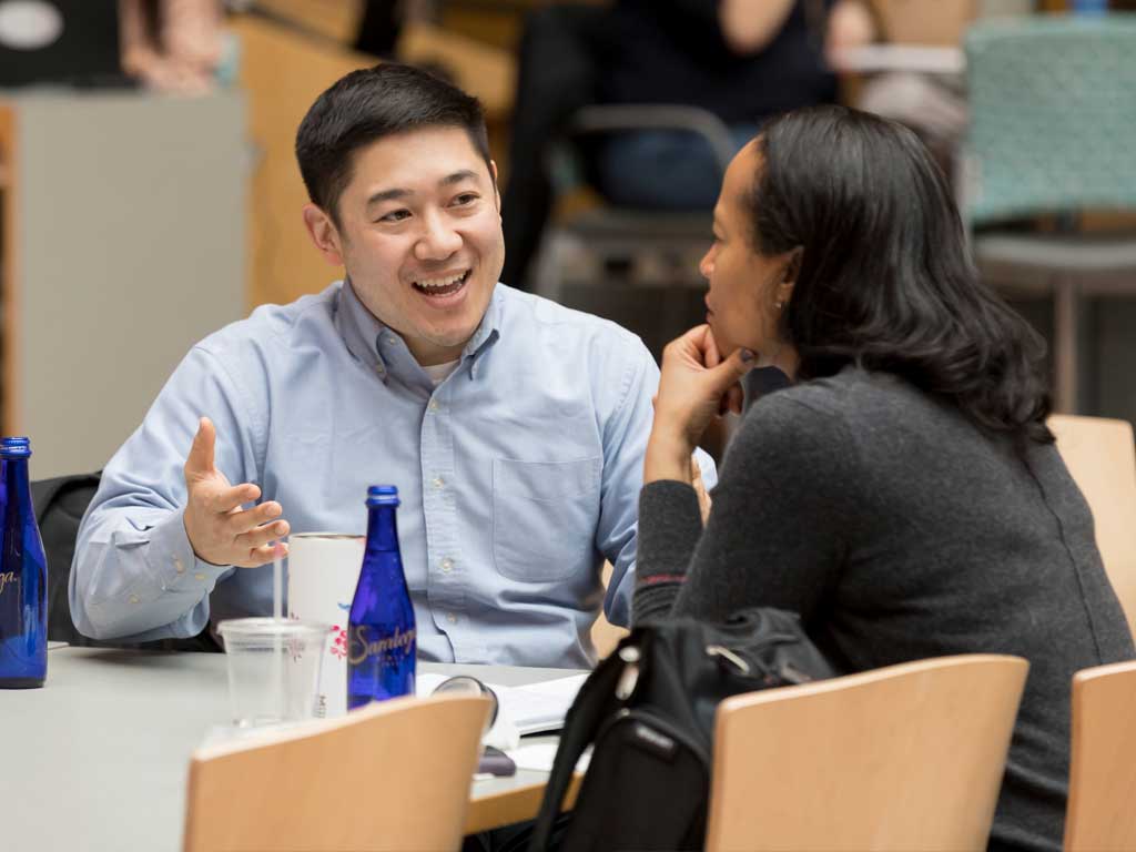 Two people sit at a table chatting.