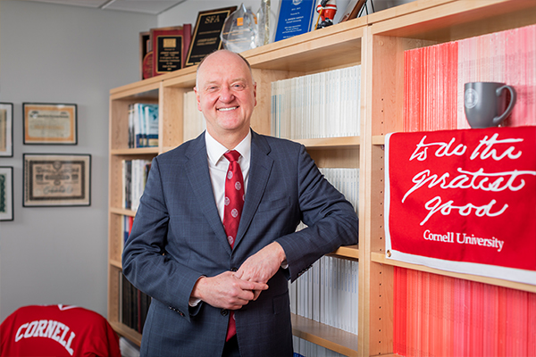 Dean Andrew Karolyi stands in his office in a suit and tie.