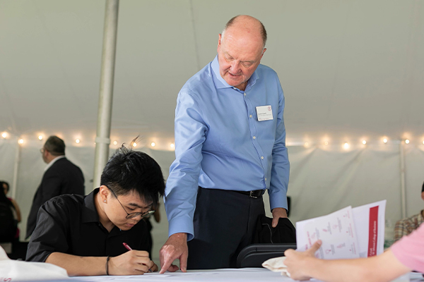 Dean Karolyi stands while a student sits and they look at a paper together.