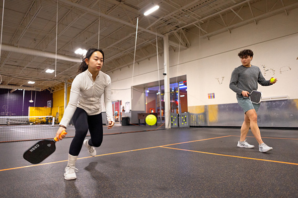 Image of a female and male student practicing pickleball at Pickleball Mania at the Shops at Ithaca Mall.