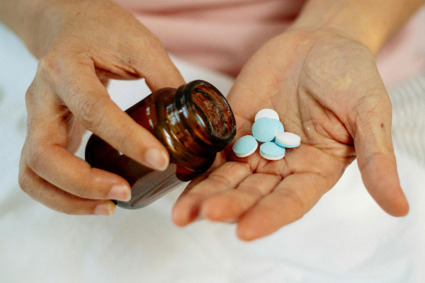 A pair of hands with a prescription bottle and pills