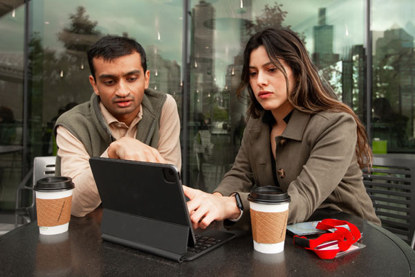 Two business analytics students reviewing data on a laptop